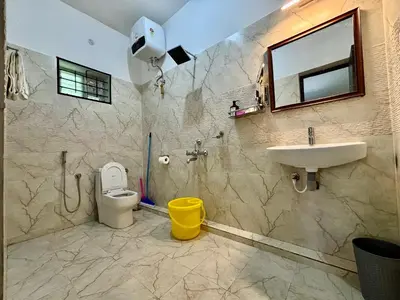 a bathroom with a sink and a toilet and a mirror at Easters home in Kotagiri