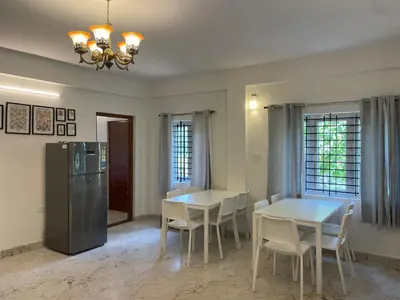 a dining room with two tables and a refrigerator at Easters home in Kotagiri