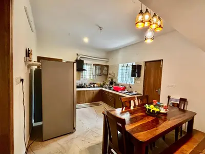 a kitchen with a wooden table and a refrigerator at Easters home in Kotagiri