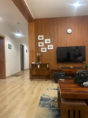 a living room with a flat screen tv on a wooden wall at Easters home in Kotagiri