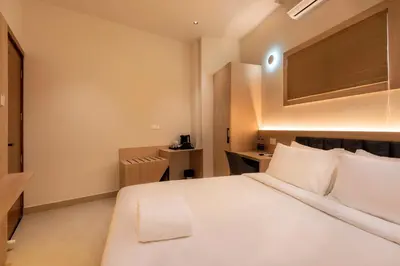 a bedroom with a large white bed and a desk at The Continental Suites in Kozhikode