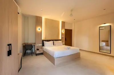 a bedroom with a bed and a desk and a mirror at The Continental Suites in Kozhikode