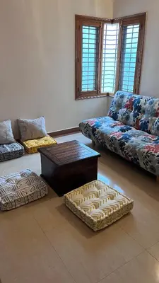 a living room with two couches and a coffee table at Aasana A tranquil space by the hills in Mysore