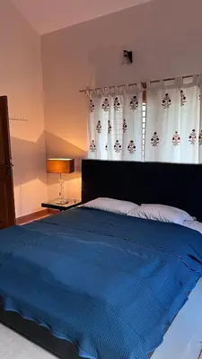 a bedroom with a large blue bed with curtains at Aasana A tranquil space by the hills in Mysore