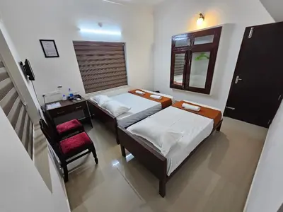 a small bedroom with two beds and a chair at Guruvayur Nest Homestay Duo in Guruvāyūr