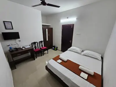 a bedroom with a bed and a desk and chairs at Guruvayur Nest Homestay Duo in Guruvāyūr
