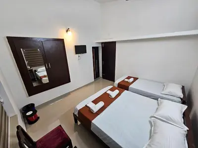 a large room with two beds and a mirror at Guruvayur Nest Homestay Duo in Guruvāyūr
