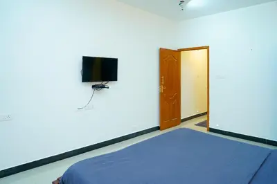 a bedroom with a bed and a tv and a door at Nature'call homestay in Ooty