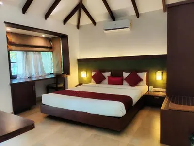 a bedroom with a large bed with red pillows at Misty Grove Resort, Gudalur in Devāla