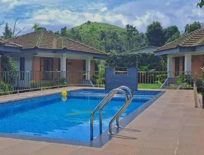 a swimming pool in front of a house at Misty Grove Resort, Gudalur in Devāla
