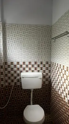a bathroom with a toilet in a tiled wall at Aneesh Arcade in Kollengode