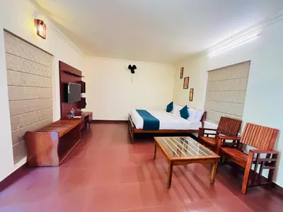 a hotel room with a bed and a table and chairs at Vythiri Greens Holiday Resorts in Vythiri