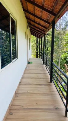 a wooden walkway leading to a building with windows at Nyra homestay in Kushālnagar