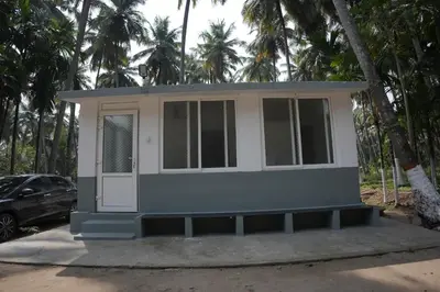 a tiny house on a street with palm trees at River view farm stay in Anaimalai