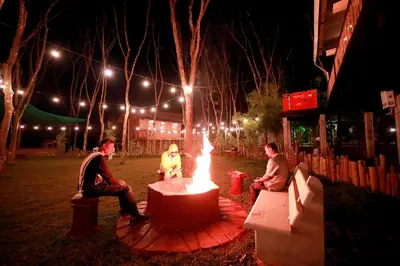 a group of people sitting around a fire pit at night at Bali Bamboo Resort in Padinjarathara