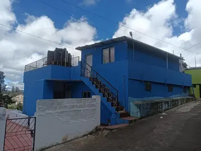 a blue building with stairs in front of it at Yamuna cottage in Ooty