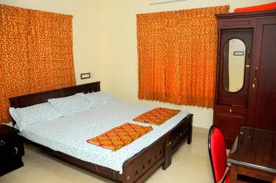 a bedroom with a bed and a dresser and a mirror at Grace Guest Home in Trichūr