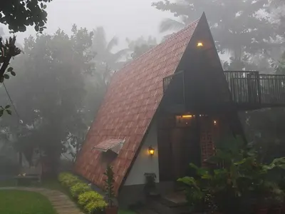a house with a red roof in the fog at Whispering Bamboos Attapadi Palakkad in Palakkad