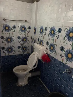 a bathroom with a toilet with blue flowers on the wall at The Retreat in Vālpārai