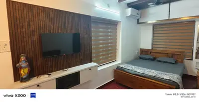 a bedroom with a bed and a flat screen tv at Pranavam homestay in Guruvāyūr