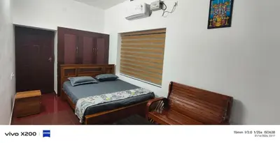 a bedroom with a bed and a wooden bench at Pranavam homestay in Guruvāyūr