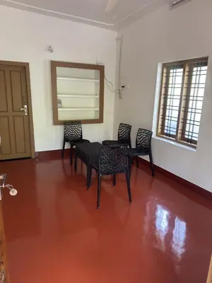 a dining room with a table and chairs on a red floor at Hibisco Hideout in Meenangadi