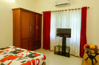 a bedroom with a bed and a tv and red curtains at River Whisper Homestay in Cochin