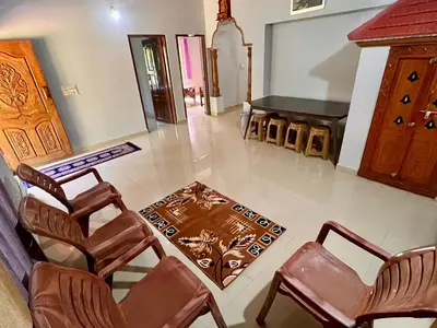 a living room with chairs and a table and a piano at Bean & Breeze in Suntikoppa