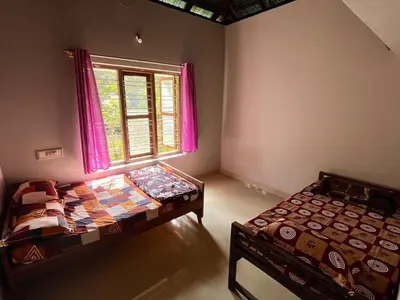 two beds in a room with a window at Bean & Breeze in Suntikoppa
