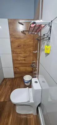 a bathroom with a white toilet and a wooden floor at Love Nest Inn Homestay in Agali