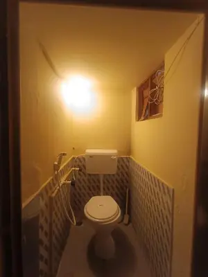 a bathroom with a toilet with a light on the wall at Holy Family Nest 2 in Mysore