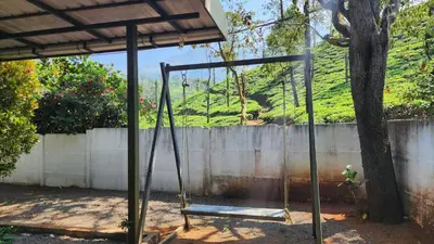 a swing in a yard next to a tree at The Bear's Lair 2BHK Chembra Peak View in Vythiri