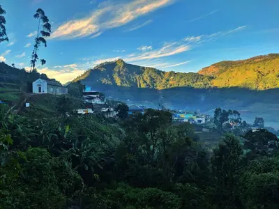a village on a hill with mountains in the background at Brooklyn Homestay in Vattavada