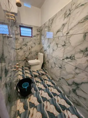 a bathroom with a toilet and a marble wall at Brooklyn Homestay in Vattavada