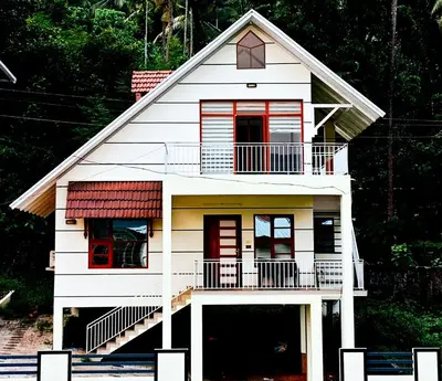 a small white house with a porch and balcony at Athirappilly resort villa in Athirappilly