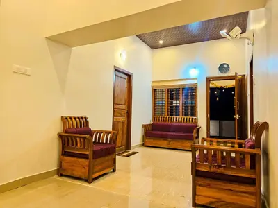 a living room with two chairs and a window at Mamoksha Riverdale in Padinjarathara
