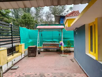 a porch of a house with a swing at White House Cottage in Ooty