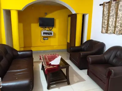 a living room with two leather couches and a basketball hoop at White House Cottage in Ooty