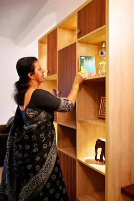 a woman is taking a book from a book shelf at Antara Luxury Homestay in Alwaye
