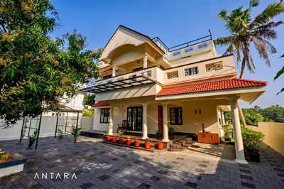 a house with a palm tree in front of it at Antara Luxury Homestay in Alwaye