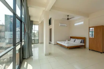 a bedroom with a bed and a large window at Grape Rooms in Perintalmanna