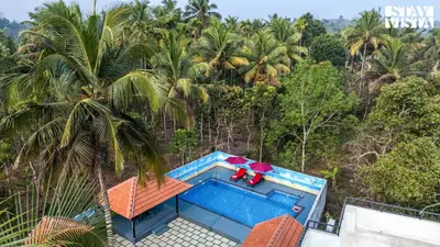 an overhead view of a swimming pool with palm trees at StayVista at Lagoons Kuruva with Shared Pool, Lawn in Chekadi