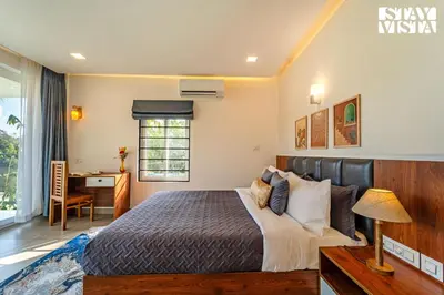 a bedroom with a bed and a desk and a window at StayVista at Lagoons Kuruva with Shared Pool, Lawn in Chekadi