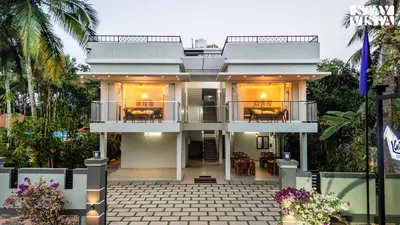 a white house with a balcony and tables at StayVista at Lagoons Kuruva with Shared Pool, Lawn in Chekadi