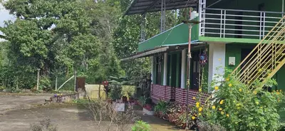 a green and white house with flowers in front of it at Coffee land in Kaniyāmbetta