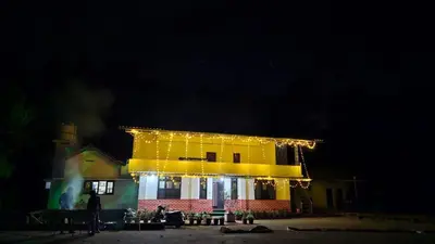 a yellow building with lights on it at night at Coffee land in Kaniyāmbetta