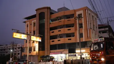 a tall building with neon signs in front of it at Stay Ease Rental Rooms in Palakkad