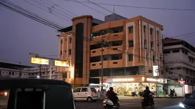 a building on a city street with people riding motorcycles at Stay Ease Rental Rooms in Palakkad