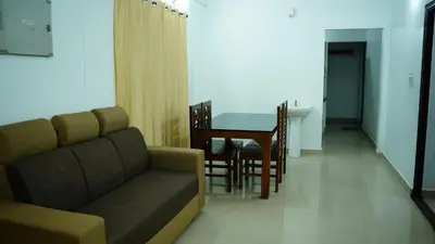 a living room with a couch and a dining room table at Stay Ease Rental Rooms in Palakkad