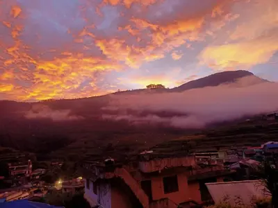 a sunset over a city with a fog covered mountain at Kalpanahomestay in Vattavada